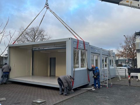 Bild des Aufstellens von Bürocontainern für temporäre Arbeitsbereiche beim Sanitätshaus Förster in Frankfurt. Schnelle Bereitstellung für den Geschäftsbetrieb während Renovierungsarbeiten.