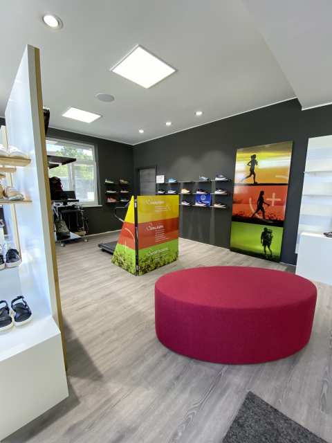 Verkaufsraum bei Fischer Fussfit in Burglengenfeld mit Sitzinsel zur Anprobe und Laufband zum Testen der orthopädischen Schuhe. Modernes Design und innovative Einrichtung für ein verbessertes Einkaufserlebnis.